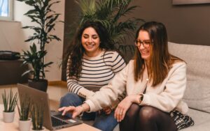 2 personnes souriantes assises devant un ordinateur