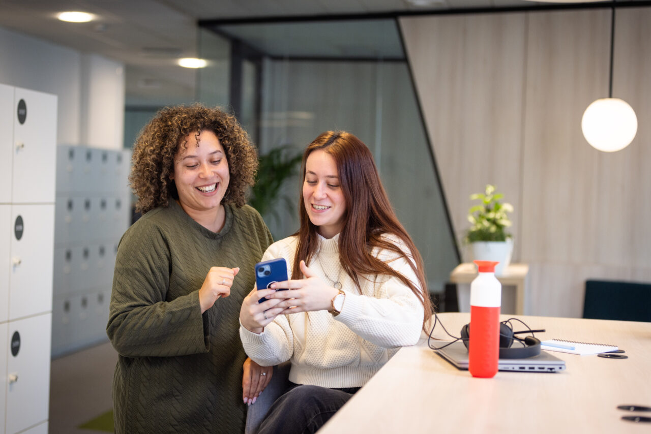 Deux personnes regardent leur téléphone en souriant